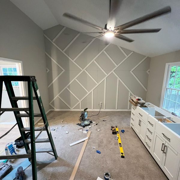 Geometric trim going up on an accent wall, with tools and a ladder in the room