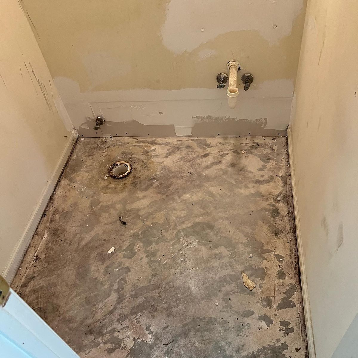 Before: a half bath stripped to the bare subfloor, with the toilet flange and supply lines exposed